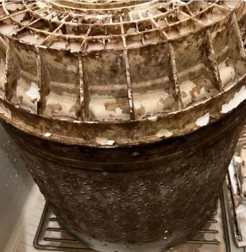 The inside of a washing machine tub with dirt buildup before cleaning